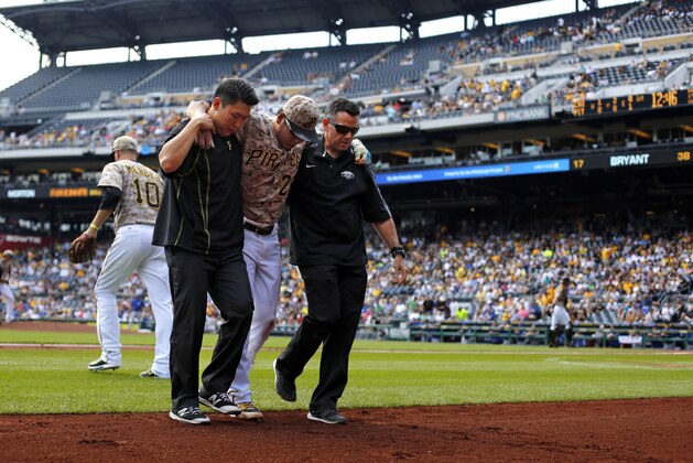 Pittsburgh Pirates shortstop Jung Ho Kang, center, is helped off the field by  team trainer, right, and his interpreter after injuring his left leg turning a double play in the first inning of a baseball game against the Chicago Cubs in Pittsburgh, Thursday, Sept. 17, 2015. Kang left the game. Entering the game to play shortstop is Pirates' Jordy Mercer (10). (AP Photo/Gene J. Puskar)