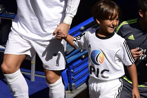 Real Madrid's Portuguese forward Cristiano Ronaldo (L) enters the pitch with Zaid, son of Osama Abdul Mohsen (C), the Syrian refugee who made world headlines when a Hungarian journalist tripped him over as he fled, before the Spanish league football match Real Madrid CF vs Granada FC at the Santiago Bernabeu stadium in Madrid on Spetember 19, 2015.   AFP PHOTO/ JAVIER SORIANO        (Photo credit should read JAVIER SORIANO/AFP/Getty Images)