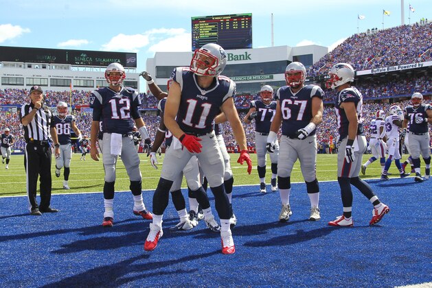New England Patriots quarterback Tom Brady (12), Dion Lewis (33) and Josh Kline (67) watch as Julian Edelman (11) spikes the ball after scoring a touchdown during the first half of an NFL football game against the Buffalo Bills Sunday, Sept. 20, 2015, in Orchard Park, N.Y. (AP Photo/Bill Wippert)