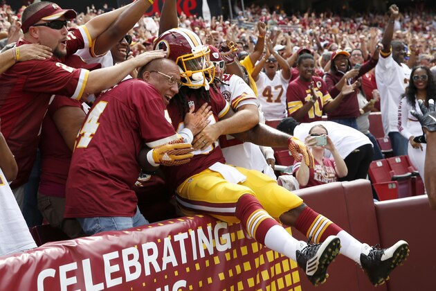 Washington Redskins running back Matt Jones jumps into the fans after scoring a touchdown during the first half of an NFL football game against the St. Louis Rams in Landover, Md., Sunday, Sept. 20, 2015. (AP Photo/Alex Brandon)