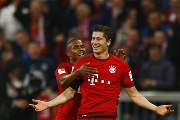 Bayern's Robert Lewandowski, right, celebrates with teammate Douglas Costa after scoring during the German Bundesliga soccer match between FC Bayern Munich and VfL Wolfsburg at the Allianz Arena stadium in Munich, Germany, Tuesday, Sept. 22, 2015. Lewandowski made Bundesliga history on Tuesday after scoring five goals in the space of nine minutes as Bayern Munich came from behind to rout Wolfsburg 5-1 and move to the top of the standings. (AP Photo/Matthias Schrader)