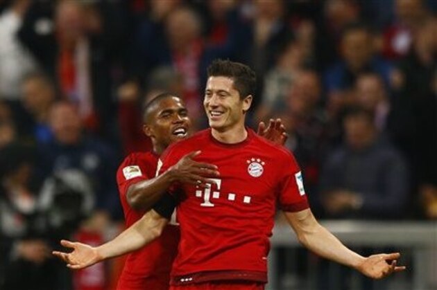 Bayern's Robert Lewandowski, right, celebrates with teammate Douglas Costa after scoring during the German Bundesliga soccer match between FC Bayern Munich and VfL Wolfsburg at the Allianz Arena stadium in Munich, Germany, Tuesday, Sept. 22, 2015. Lewandowski made Bundesliga history on Tuesday after scoring five goals in the space of nine minutes as Bayern Munich came from behind to rout Wolfsburg 5-1 and move to the top of the standings. (AP Photo/Matthias Schrader)
