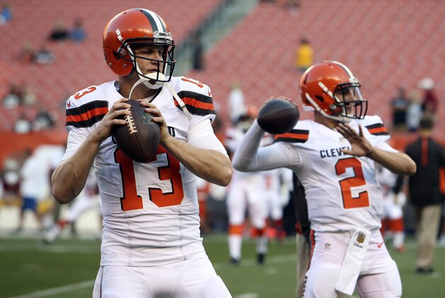 In this Thursday, Aug. 13, 2015 photo, Cleveland Browns quarterbacks Josh McCown (13) and Johnny Manziel (2) warm up before an NFL preseason football game between the Browns and the Washington Redskins in Cleveland. McCown doesn't view Manziel as a threat, but as a teammate to teach. The veteran quarterback was signed by Cleveland to stabilize the position and help Manziel following his turbulent rookie season. So far, the plan has been flawless. (AP Photo/Ron Schwane)