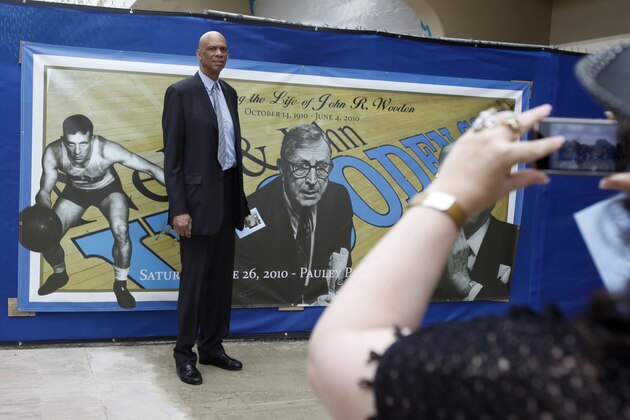 Former UCLA and Lakers great Kareem Abdul-Jabbar poses for a photo by a commorative banner as he arrives for a memorial service for the late UCLA basketball coach John Wooden, at Pauley Pavilion in Los Angeles, Saturday, June 26, 2010. (AP Photo/Reed Saxon)