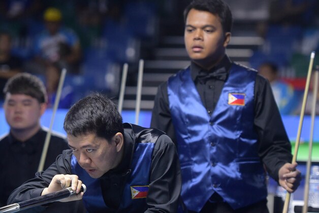 Warren Kiamco of Philippines, second right, plays in the men's 9-ball pool doubles semifinals match as his compatriot Carlo Biado, right, and opponents from Singapore, Toh Lian Han, left, and Aloysius Yapp look on at the SEA Games in Singapore, Sunday, June 7, 2015.(AP Photo/Joseph Nair)