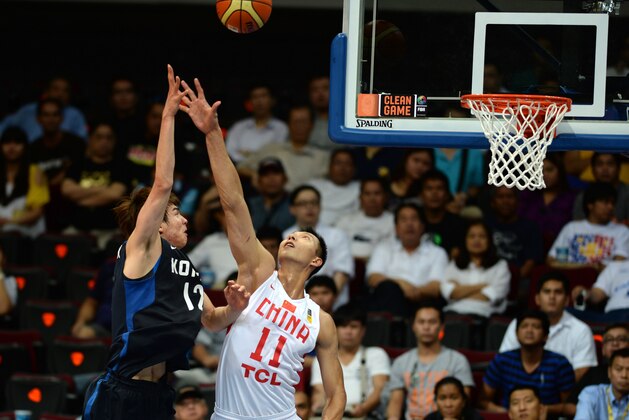 China's Yi Jianlian  (R) tries to block a shot by South Korea's Kim Jongkyu during the Asian Basketball championships for men in Manila on August 1, 2013. South Korea won 63-59.    AFP PHOTO/TED ALJIBE        (Photo credit should read TED ALJIBE/AFP/Getty Images)