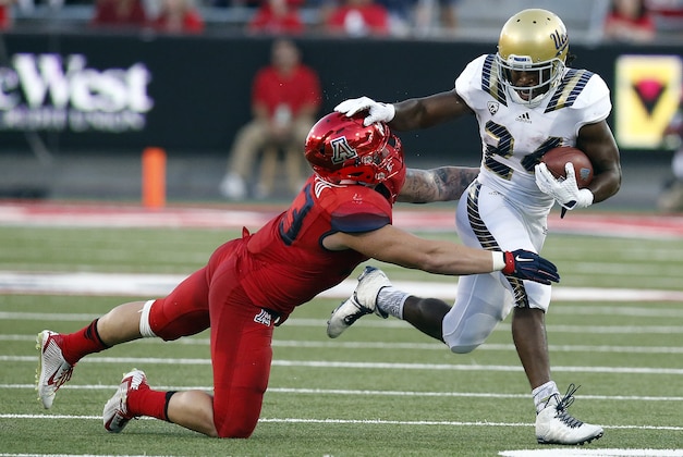UCLA running back Paul Perkins (24) stiff-arms Arizona linebacker Scooby Wright III during the first half of an NCAA college football game, Saturday, Sept. 26, 2015, in Tucson, Ariz. (AP Photo/Rick Scuteri)