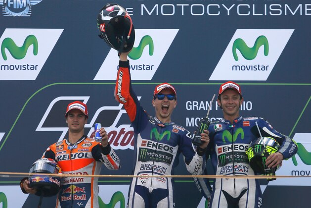 Moto GP rider Jorge Lorenzo of Spain, center, celebrates on the podium after winning  the Aragon Motorcycle Grand Prix at the Aragon Motorland racetrack in Alcaniz, Spain, Sunday, Sept. 27, 2015. At left is second placed Dani Pedrosa of Spain and at right is third placed Valentino Rossi of Italy. (AP Photo/Francisco Seco)