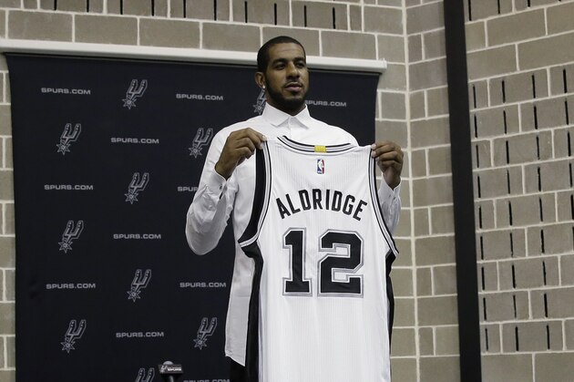 LaMarcus Aldridge poses with his new jersey during a news conference at the team's practice facility as he is formally introduced after he signed with the San Antonio Spurs NBA basketball team, Friday, July 10, 2015, in San Antonio. (AP Photo/Eric Gay)