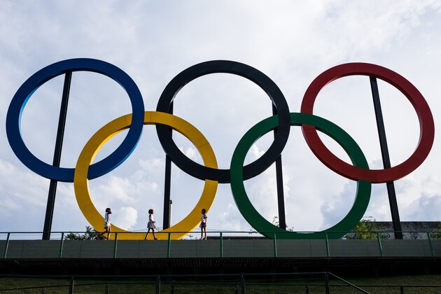 Youngsters walk past the Olympic rings at Madureira Park, the third largest park in Rio de Janeiro, Brazil, on July 1, 2015, 400 days ahead of the Rio 2016 Olympic games. The 12-meter-high symbol was shipped from Great Britain after having decorated the Tyne Bridge in Newcastle during the 2012 London Olympic Games. AFP PHOTO / YASUYOSHI CHIBA        (Photo credit should read YASUYOSHI CHIBA/AFP/Getty Images)