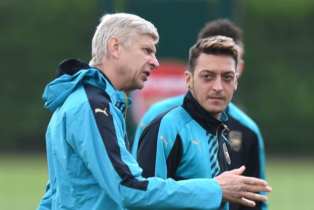 Arsenal manager Arsene Wenger (L) talks with German midfielder Mesut Ozil during a training session at London Colney in St Albans, north London on 28 September, 2015 before a Group F Champions League football match against Olympiakos.  
AFP PHOTO/Olly Greenwood        (Photo credit should read OLLY GREENWOOD/AFP/Getty Images)