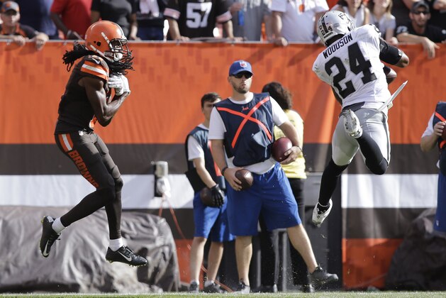 Oakland Raiders free safety Charles Woodson, right, catches an interception intended for Cleveland Browns wide receiver Travis Benjamin during the second half of an NFL football game, Sunday, Sept. 27, 2015, in Cleveland.Oakland won 27-20.(AP Photo/Aaron Josefczyk)