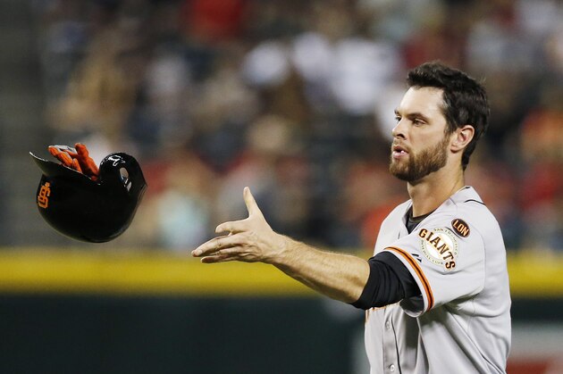 San Francisco Giants' Brandon Belt tosses his helmet and batting gloves to a batboy during the fourth inning of a baseball game against the Arizona Diamondbacks Tuesday, Sept. 8, 2015, in Phoenix. (AP Photo/Ross D. Franklin)