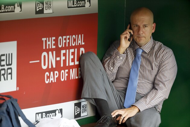 Atlanta Braves assistant general manager and director of pro scouting John Coppolella talks on the phone in the dugout during batting practice before a baseball game against the Washington Nationals at Nationals Park, Friday, Sept. 4, 2015, in Washington. (AP Photo/Alex Brandon)
