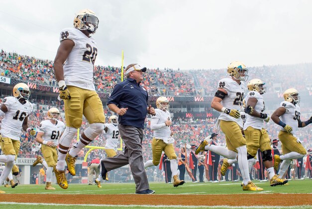Sep 12, 2015; Charlottesville, VA, USA; Notre Dame Fighting Irish running back C.J. Prosise (20) and head coach Brian Kelly run onto the field before the game against the Virginia Cavaliers at Scott Stadium. Mandatory Credit: Matt Cashore-USA TODAY Sports