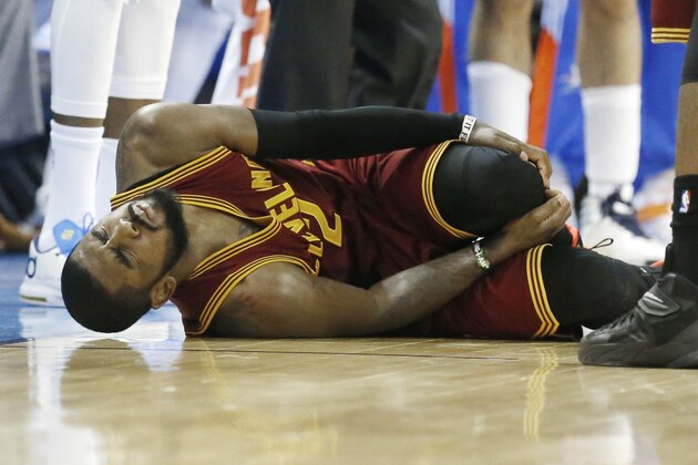 Cleveland Cavaliers guard Kyrie Irving grimaces as he holds his knee following an injury in the second quarter of an NBA basketball game against the Oklahoma City Thunder in Oklahoma City, Thursday, Dec. 11, 2014. (AP Photo/Sue Ogrocki)