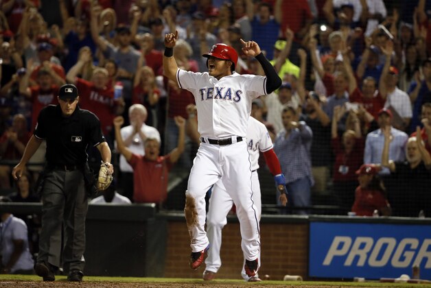 Home plate umpire Quinn Wolcott watches as Texas Rangers' Shin-Soo Choo of South Korea celebrates scoring on a bases clearing double hit by Adrian Beltre against the Los Angeles Angels in the fifth inning of a baseball game Thursday, Oct. 1, 2015, in Arlington, Texas. The hit also scored Delino DeShields and Robinson Chirinos.  (AP Photo/Tony Gutierrez)