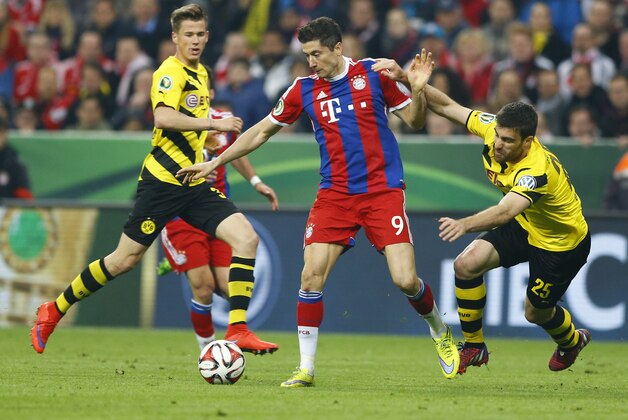 Bayern's Robert Lewandowski, center, and Dortmund's Erik Durm, left, and Dortmund's Sokratis challenge for the ball during the German soccer cup (DFB Pokal) semifinal match between FC Bayern Munich and Borussia Dortmund at the Allianz Arena in Munich, Germany, on Tuesday, April 28, 2015. (AP Photo/Matthias Schrader)