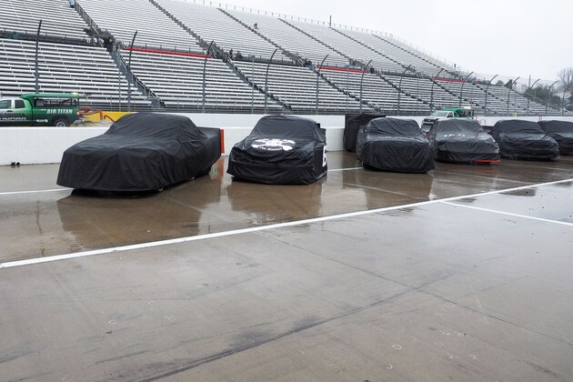 Trucks sit under covers as Air Titans try to keep the track dry during a rain delay at the  NASCAR Truck Series auto race at Martinsville Speedway in Martinsville, Va., Saturday, March 29, 2014. (AP Photo/Steve Sheppard)