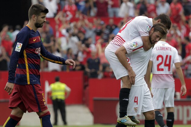 Barcelona's Gerard Pique, left, looks on as Sevilla's Grzegorz Krychowiak, right, and Coke, celebrate at the end of the match during their La Liga soccer match at the Ramon Sanchez Pizjuan stadium, in Seville, Spain on Saturday, Oct. 3, 2015. Sevilla won 2-1(AP Photo/Miguel Angel Morenatti)