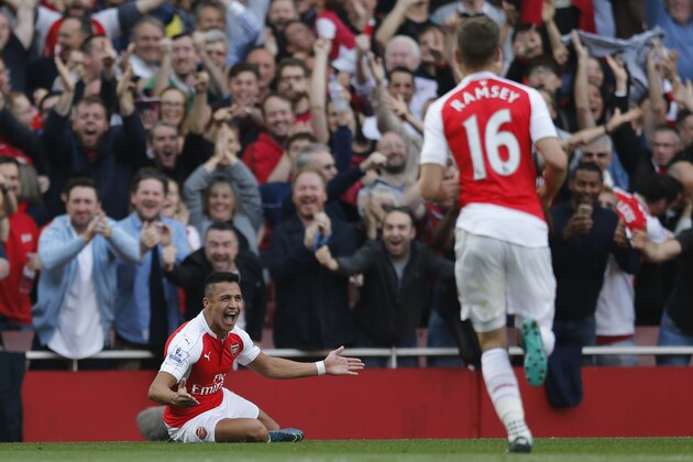 Arsenal's Alexis Sanchez, left, looks round as he celebrates with teammates after scoring his second goal of the game during the English Premier League soccer match between Arsenal and Manchester United at Emirates stadium in London, Sunday, Oct. 4, 2015.(AP Photo/Frank Augstein)