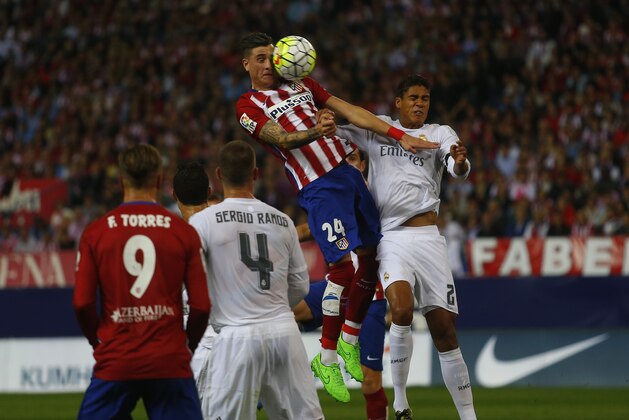 Atletico Madrid's Jose Gimenez, top, goes for a header with Real Madrid's Raphael Varane, right, during a Spanish La Liga soccer match between Real Madrid and Atletico Madrid at the Vicente Calderon stadium in Madrid, Sunday, Oct. 4, 2015. (AP Photo/Francisco Seco)