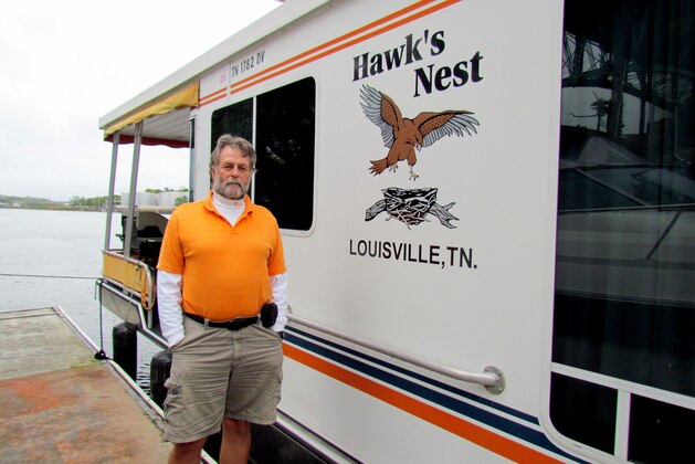 Coy Caldwell stands alongside his houseboat that stays docked near Neyland Stadium all through college football season.