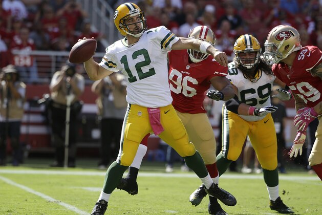 Green Bay Packers quarterback Aaron Rodgers (12) passes as San Francisco 49ers linebacker Corey Lemonier (96) applies pressure during the first half of an NFL football game in Santa Clara, Calif., Sunday, Oct. 4, 2015. (AP Photo/Marcio Jose Sanchez)