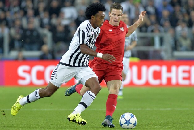 Juventus' Juan Cuadrado, left, and Sevilla's Kevin Gameiro fight for the ball during  the Champions League group D soccer match between Juventus and FC Sevilla, at the Juventus Stadium in Turin, Italy, Wednesday, Sept. 30, 2015. (AP Photo/Massimo Pinca)