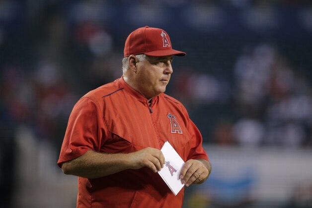 Los Angeles Angels manager Mike Scioscia, center, walks onto the field with the team's official batting order before a baseball game against the Los Angeles Dodgers, Wednesday, Sept. 9, 2015, in Anaheim, Calif. (AP Photo/Jae C. Hong)