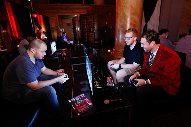 IMAGE DISTRIBUTED FOR 2K - Media representatives pictured from left to right, Victor Ferreira, James Darnell and Anthony Whitver, try out WWE 2K16 at demo stations during the WWE 2K SummerSlam Kickoff in New York, N.Y., in Thursday, Aug. 20, 2015. (Photo by Stuart Ramson/Invision for 2K/AP Images)