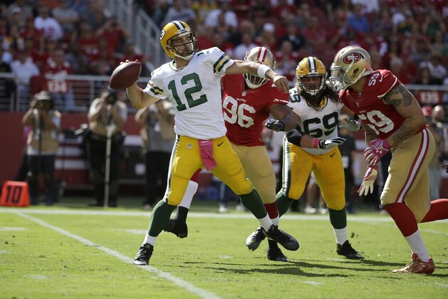 Green Bay Packers quarterback Aaron Rodgers (12) passes as San Francisco 49ers linebacker Corey Lemonier (96) applies pressure during the first half of an NFL football game in Santa Clara, Calif., Sunday, Oct. 4, 2015. (AP Photo/Marcio Jose Sanchez)