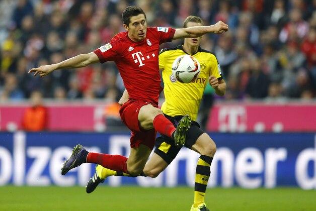 Bayern's Robert Lewandowski, foreground, challenges for the ball to score his side's third goal during the German Bundesliga soccer match between FC Bayern Munich and Borussia Dortmund at the Allianz Arena stadium in Munich, Germany, Sunday, Oct. 4, 2015. (AP Photo/Matthias Schrader)