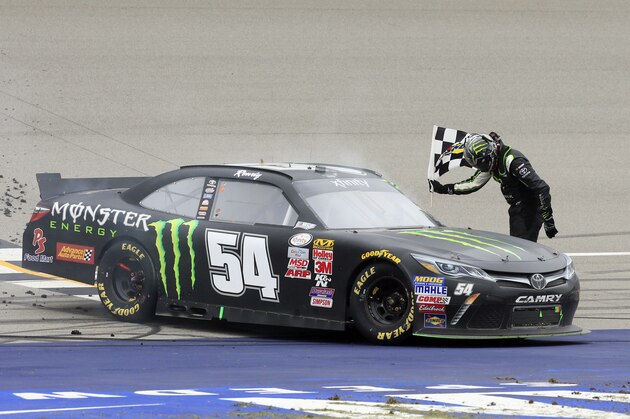 Kyle Busch bows to the crowd at the finish line after winning the NASCAR Xfinity series auto race at Michigan International Speedway, Saturday, June 13, 2015, in Brooklyn, Mich. (AP Photo/Carlos Osorio)