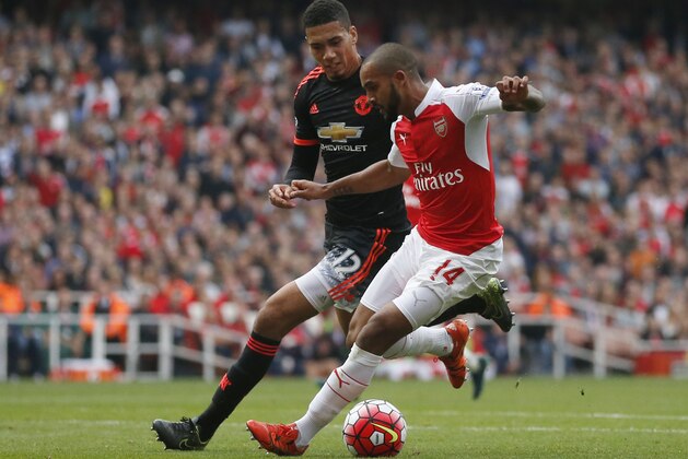 Arsenal's Theo Walcott, right,  shield the ball from Manchester United's Chris Smalling during the English Premier League soccer match between Arsenal and Manchester United at Emirates stadium in London, Sunday, Oct. 4, 2015.(AP Photo/Frank Augstein)