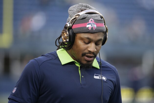 Seattle Seahawks running back Marshawn Lynch stands on the field during warmups before an NFL football game against the Detroit Lions, Monday, Oct. 5, 2015, in Seattle as he wears a hat for breast cancer awareness. Lynch was not expected to play in the game due to an injury. (AP Photo/Elaine Thompson)