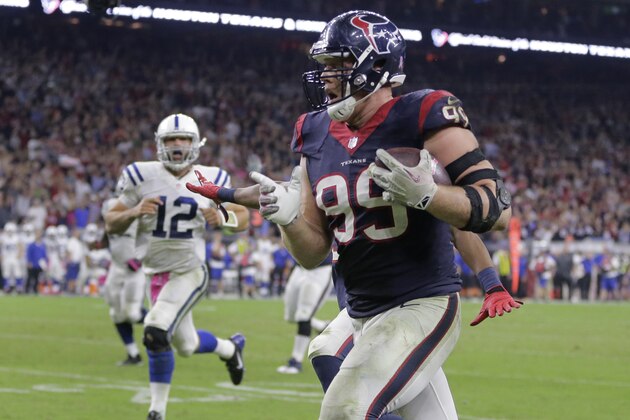 J.J. Watt (99), de los Texans de Houston, es perseguido por Andrew Luck (12), de los Colts de Indianapolis, mientras se encamina a anotar un touchdown de 45 yardas durante un partido de la NFL, el jueves 9 de octubre de 2014, en Houston. Los Texans ganaron 33-28. (AP Foto/Patric Schneider)