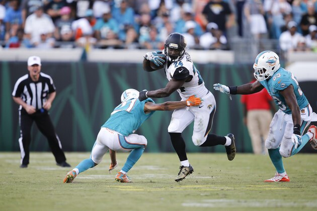 Jacksonville Jaguars running back T.J. Yeldon, center, runs between Miami Dolphins cornerback Brent Grimes, left, and outside linebacker Jelani Jenkins (53) during the second half of an NFL football game in Jacksonville, Fla., Sunday, Sept. 20, 2015.(AP Photo/Stephen B. Morton)