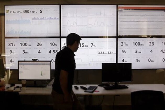 In this Wednesday, Sept. 9, 2015, photo, an employee in the software development department of DraftKings, a daily fantasy sports company, walks past screens displaying the company's online system stats in Boston. The daily fantasy sports industry is eyeing a breakout season as NFL games begin. And its two dominant companies, DraftKings and FanDuel, are touting lucrative opening week prizes to try to draw more customers as more competitors pop up. (AP Photo/Stephan Savoia)