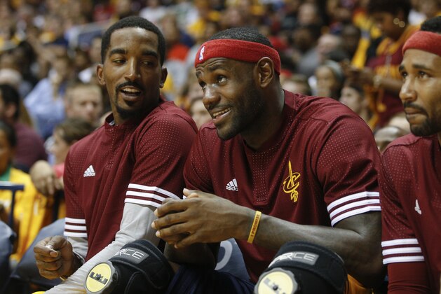 Cleveland Cavaliers forward LeBron James, center, smiles alongside guard J.R. Smith, left, as they sit on the bench in the second half of an NBA preseason basketball game against the Atlanta Hawks, Wednesday, Oct. 7, 2015, in Cincinnati. The Hawks won 98-96. (AP Photo/John Minchillo)