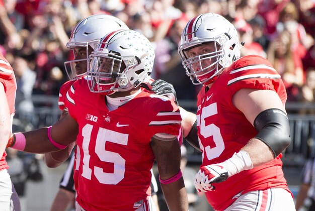 Oct 10, 2015; Columbus, OH, USA; Ohio State Buckeyes running back Ezekiel Elliott (15) is congratulated by quarterback J.T. Barrett (16) and offensive lineman Pat Elflein (65) after his touchdown against the Maryland Terrapins at Ohio Stadium. Mandatory Credit: Greg Bartram-USA TODAY Sports