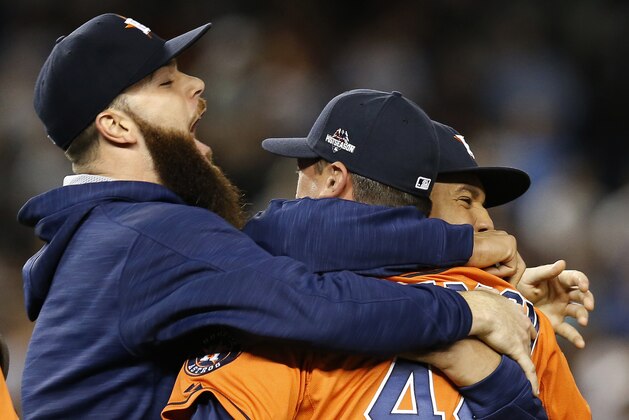 Houston Astros starting pitcher Dallas Keuchel, left, embraces Astros relief pitcher Luke Gregerson (44) and center fielder Carlos Gomez, right, as they celebrate the Astros 3-0 shutout of the New York Yankees in the American League wild card baseball game at Yankee Stadium in New York, Tuesday, Oct. 6, 2015.  (AP Photo/Kathy Willens)