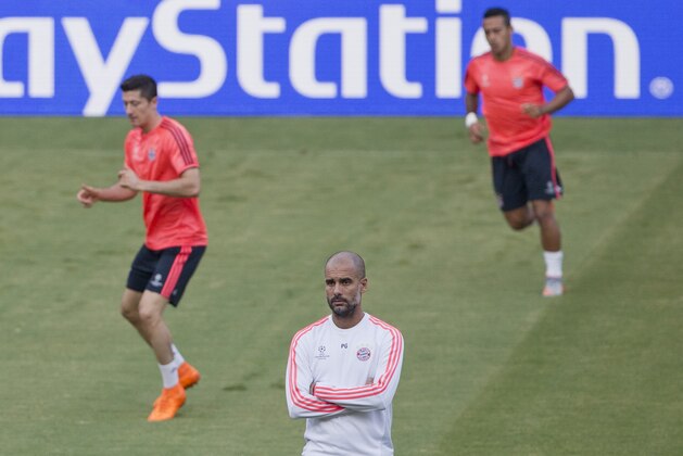 Bayern's head coach Pep Guardiola, center, looks on as his player Robert Lewandowski , eft, warms up during a training session at the Georgios Karaiskakis stadium in Piraeus port, near Athens, Tuesday, Sept. 15, 2015. Bayern Munich will play against Olympiakos on Wednesday in a Champions League Group F soccer match. (AP Photo/Petros Giannakouris)