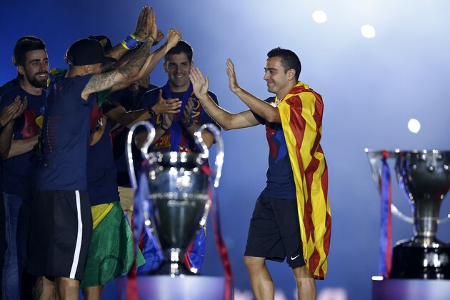 Barcelona's Xavi Hernandez, right, is welcomed to the stage by team mates during celebrations at the Camp Nou stadium in Barcelona, Spain Sunday June 7, 2015 after winning the Champions League final soccer match Saturday by beating Juventus Turin 3-1. Barcelona won the triple this season winning the Spanish League title, the Copa del Rey and the Champions League. (AP Photo/Manu Fernandez)