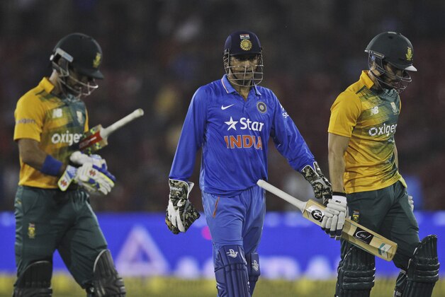 South African batsmen Farhaan Behardien, right, Jean-Paul Duminy , left and Indian captain Mahendra Singh Dhoni, center, walk back as their second Twenty20 cricket match is disrupted after spectators threw bottles in Cuttack, India, Monday, Oct. 5, 2015. (AP Photo/Biswaranjan Rout)