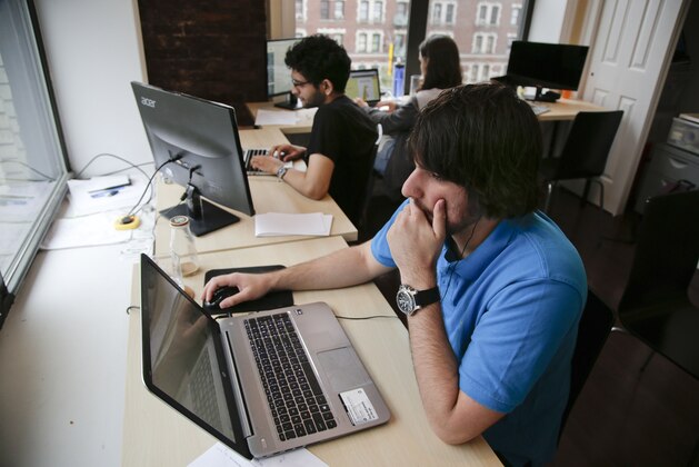 Draftpot co-founder and CEO Joey Levy, foreground, works with co-founder and CTO Joshua Hughes, center, and co-founder and developer Jessica Vandebon at the Fantasy Football operation's workspace, Wednesday, Sept. 30, 2015, in New York. After starting up from their dorm rooms at Columbia University earlier this year, the operation paid out $220,000 in it's first week online. (AP Photo/Julie Jacobson)
