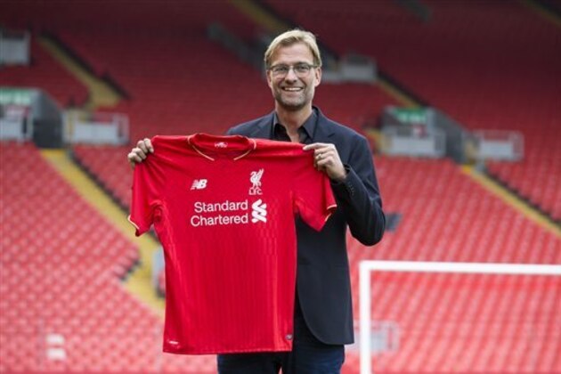 Liverpool's new manager Juergen Klopp poses for pictures in front of the Spion Kop stand after being appointed the club's new manager on a three-year deal, Liverpool, England, Friday, Oct. 9, 2015. The 48-year-old German has been out of work since May, when he ended a seven-year spell at Borussia Dortmund to take a sabbatical. (AP Photo/Jon Super)