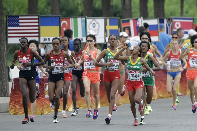 Competitors take a drink as she races through the streets of Beijing during the women's marathon at the World Athletic Championships, Sunday, Aug. 30, 2015. (AP Photo/Wong Maye-E)