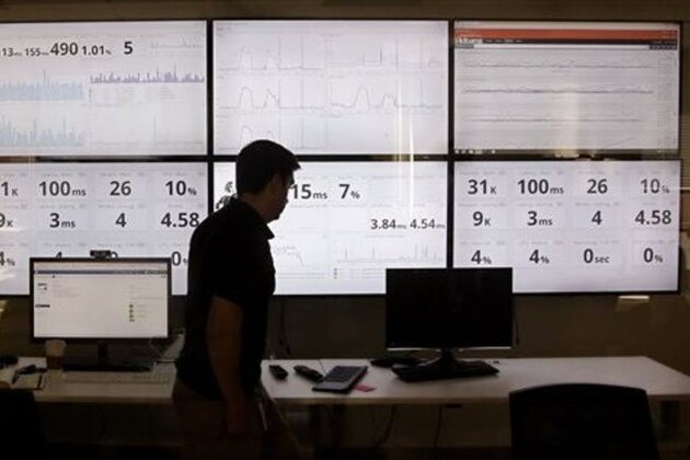 In this Wednesday, Sept. 9, 2015, photo, an employee in the software development department of DraftKings, a daily fantasy sports company, walks past screens displaying the company's online system stats in Boston. The daily fantasy sports industry is eyeing a breakout season as NFL games begin. And its two dominant companies, DraftKings and FanDuel, are touting lucrative opening week prizes to try to draw more customers as more competitors pop up. (AP Photo/Stephan Savoia)