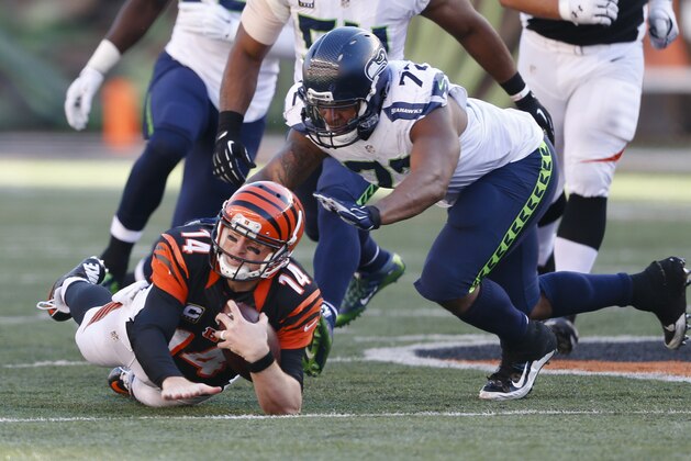 Cincinnati Bengals quarterback Andy Dalton (14) dives for extra yards on a run against Seattle Seahawks defensive end Michael Bennett (72) in overtime of an NFL football game, Sunday, Oct. 11, 2015, in Cincinnati. (AP Photo/Gary Landers)